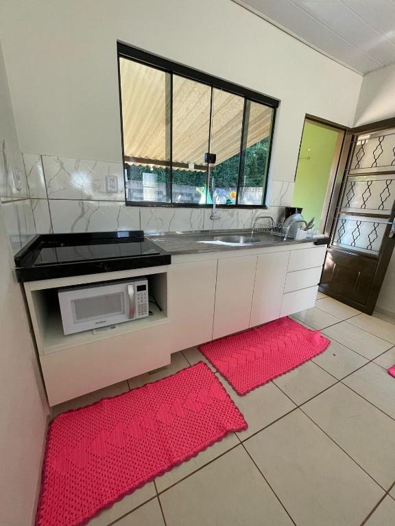 a kitchen with a sink and a microwave at Sua casa em Dourados in Dourados
