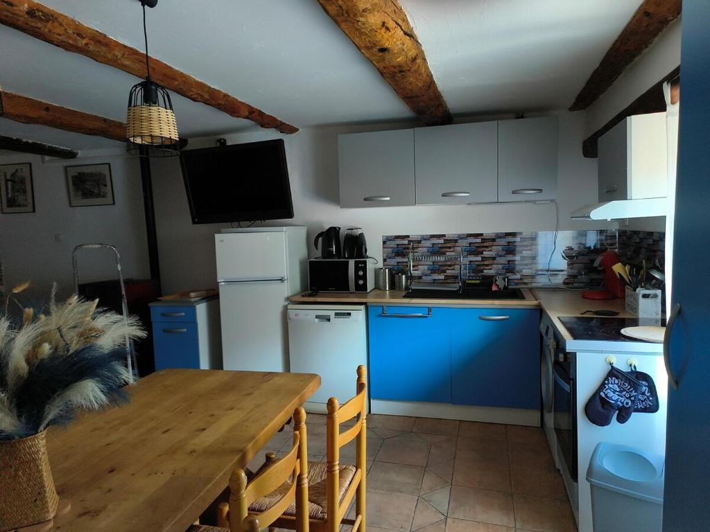 une cuisine avec des placards bleus et une table en bois dans l'établissement Mas de Chalvagne Gite confortable pour 5 personnes, à Val-de-Chalvagne