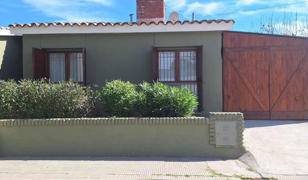 a house with a wooden door and a fence at La casa, alquiler temporario - casa completa con cochera y patio- parrilla in Villa Mercedes