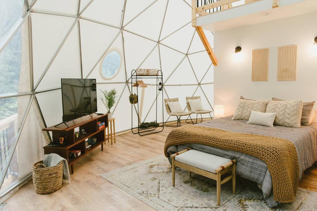 ein Schlafzimmer mit einem Bett und einem Fernseher in einer Glaswand in der Unterkunft "Home Sweet Dome" MODERN TREEHOUSE STAY w/ Hot Tub in Rogers