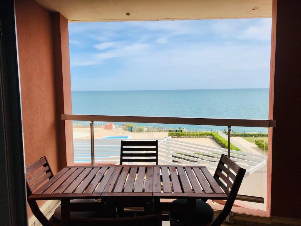- un balcon avec une table et des chaises en bois et l'océan dans l'établissement ''578'' Superbe T2 Front de mer, Parking, Clim, à Sète