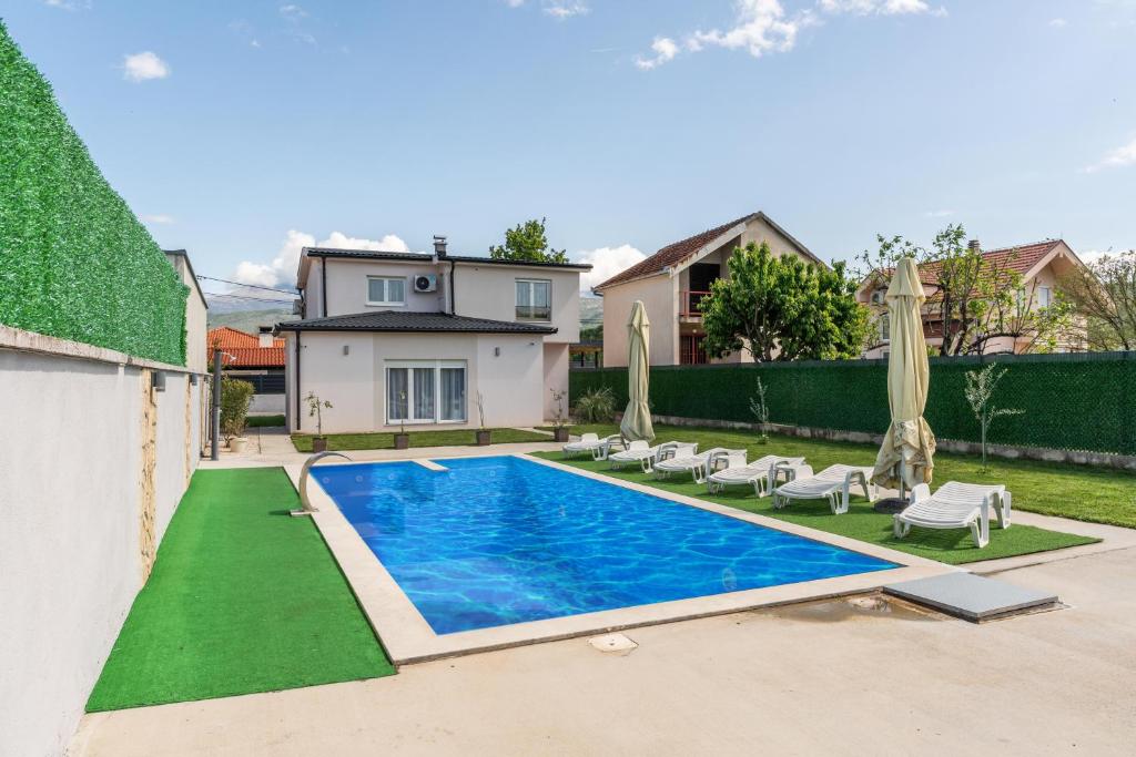a swimming pool with chairs and umbrellas in a backyard at Villa Deluxe Buna in Mostar