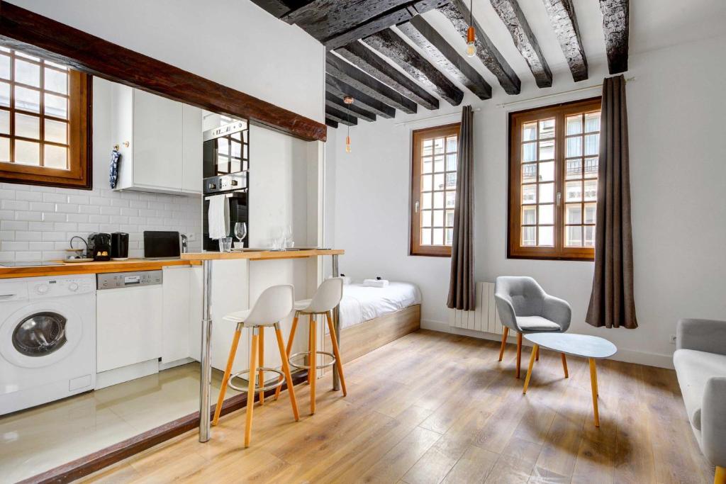 - une cuisine avec des armoires et des chaises blanches dans la chambre dans l'établissement Luminous flat in le marais, à Paris