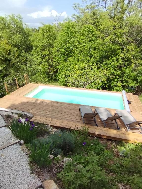 une piscine avec une terrasse en bois et des chaises autour dans l'établissement Le Petit Paradis, à Saint-Martin-de-Castillon