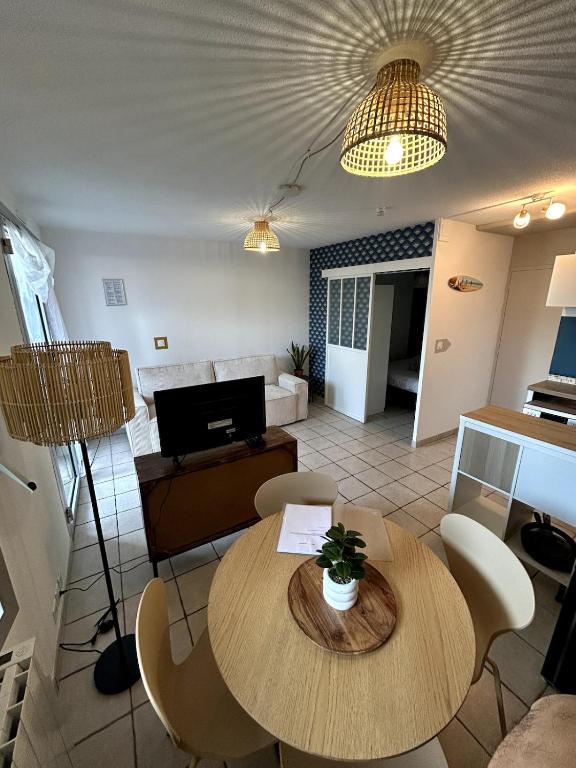 un salon avec une table, des chaises et un canapé dans l'établissement Jolie T2 avec terrasse proche plage, à Soulac-sur-Mer