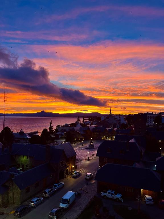 a sunset over a city with cars parked in a parking lot at Nothofagus Apartments in San Carlos de Bariloche