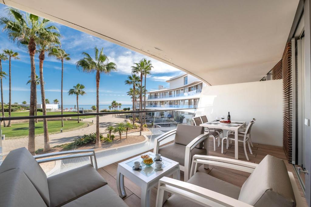 a balcony with chairs and tables and a view of the ocean at Edge Beachfront 2BR - 3 pools, 1 heated, spa, gym, cowork in Estepona