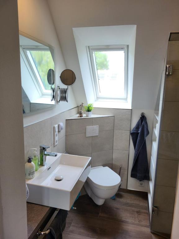 a bathroom with a toilet and a sink and two windows at Ferienwohnung Lillian in Bad Zwischenahn