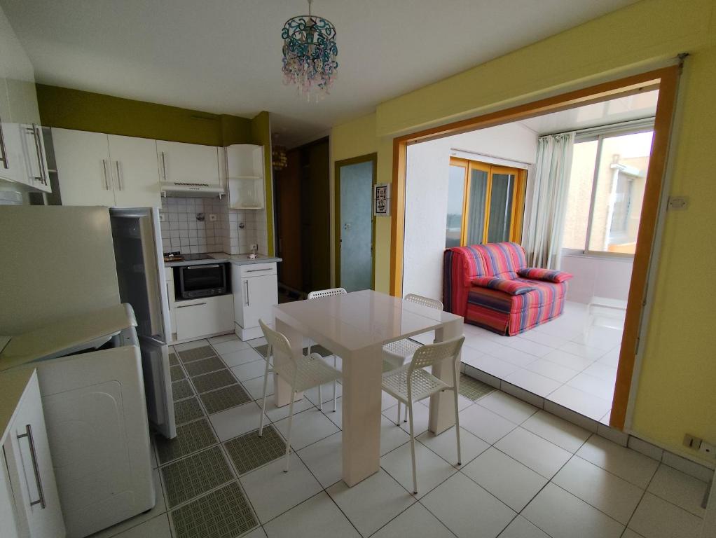 une cuisine avec une table et des chaises dans une pièce dans l'établissement Appart T2 en front de mer - chambre séparée -parking- terrasse couverte, au Barcarès