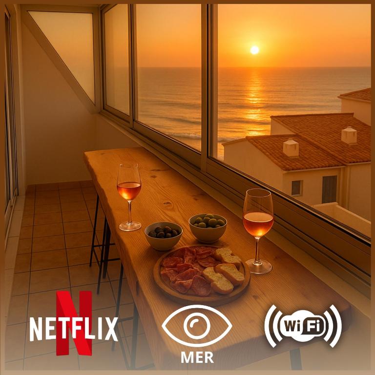 une table avec une assiette de nourriture et deux verres de vin dans l'établissement L'Échappée Vendéenne - T2 cosy en bord de mer, à Saint-Hilaire-de-Riez