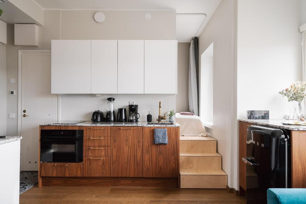 una cucina con armadietti bianchi e una scala di Comfy Top Floor Studio Apt in Centre of Helsinki a Helsinki
