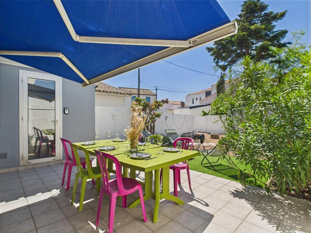 une table verte avec des chaises roses et un parasol bleu dans l'établissement Entre coeur de ville et plage, maison pour 6, à Saint-Gilles-Croix-de-Vie