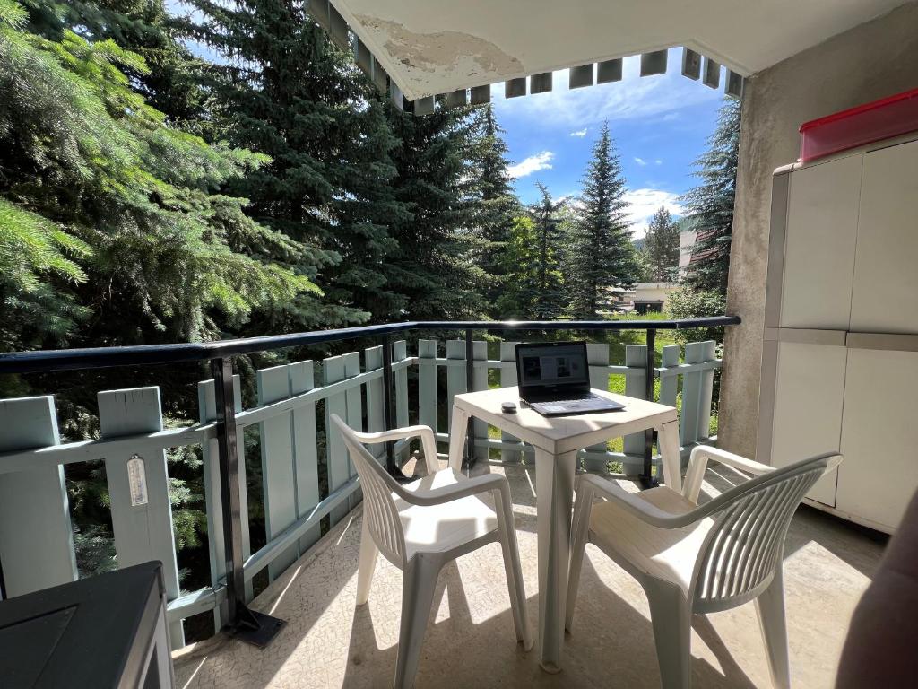 - un balcon avec une table, deux chaises et un ordinateur portable dans l'établissement Le chardon bleu, à La Salle Les Alpes