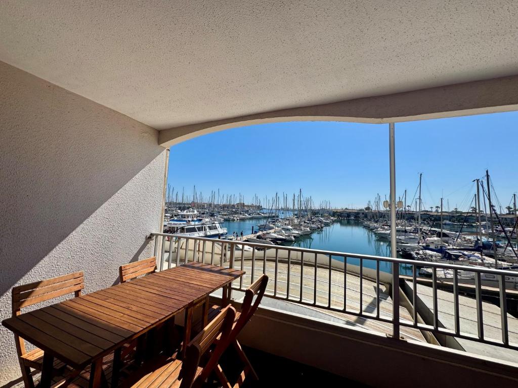 un balcon avec une table et des chaises en bois et une marina dans l'établissement Appartement - Cap d'Agde, au Cap d'Agde