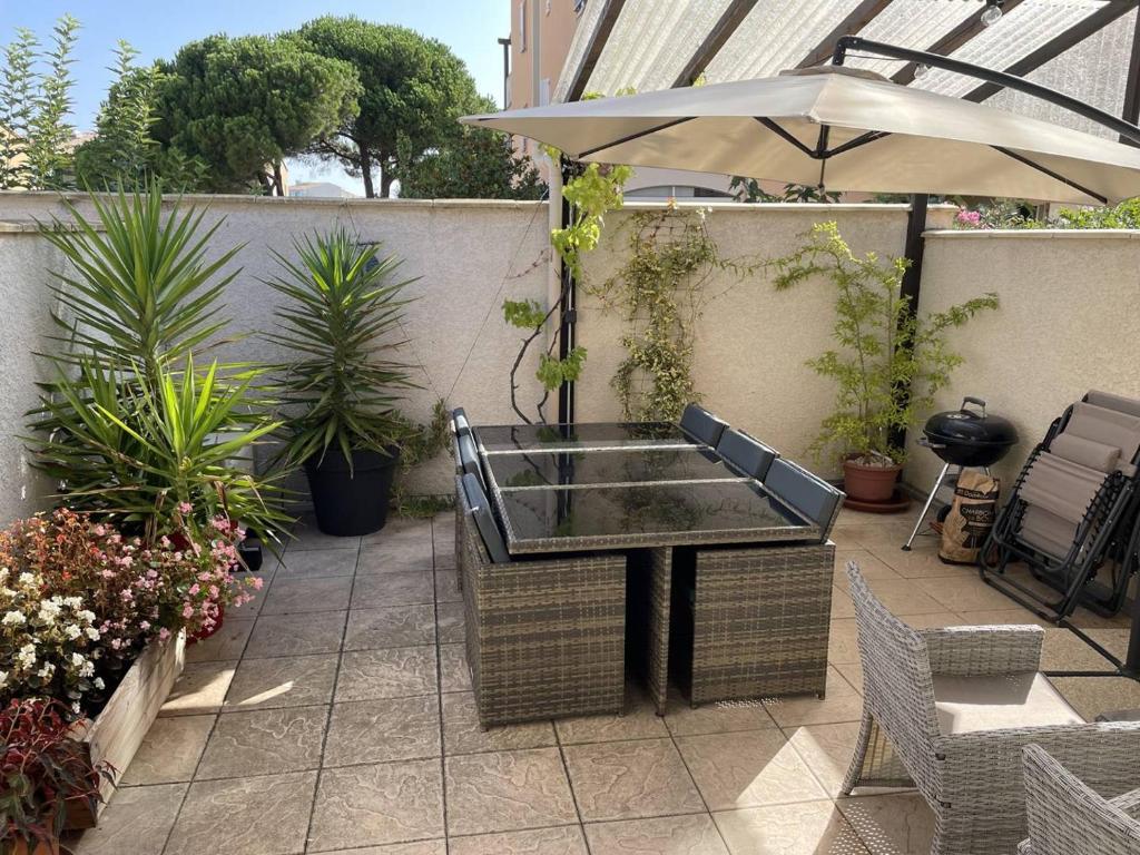 une terrasse avec une table, un parasol et des plantes dans l'établissement DELPHEAPOLIS Joli T2 mezzanine climatisé Richelieu Cap d'Agde, au Cap d'Agde