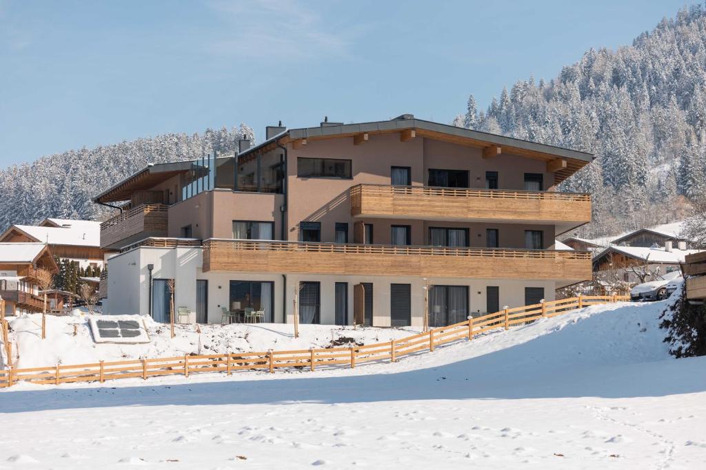 a building in the snow in front of a mountain at Alpine Collection Wildschönau in Niederau
