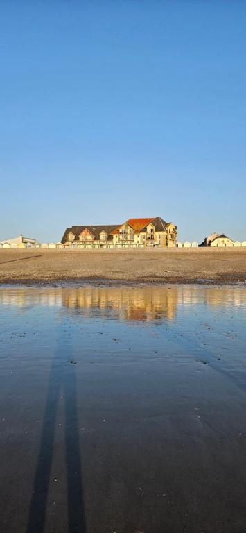 un reflet des maisons dans l'eau sur une plage dans l'établissement Le Nid Bleu Confort & Mer à Pied, à Cayeux-sur-Mer