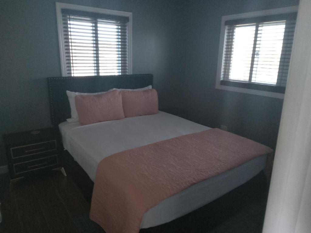 - une chambre avec un lit avec des oreillers roses et 2 fenêtres dans l'établissement Vacation Haven Cottages, à Rolleville