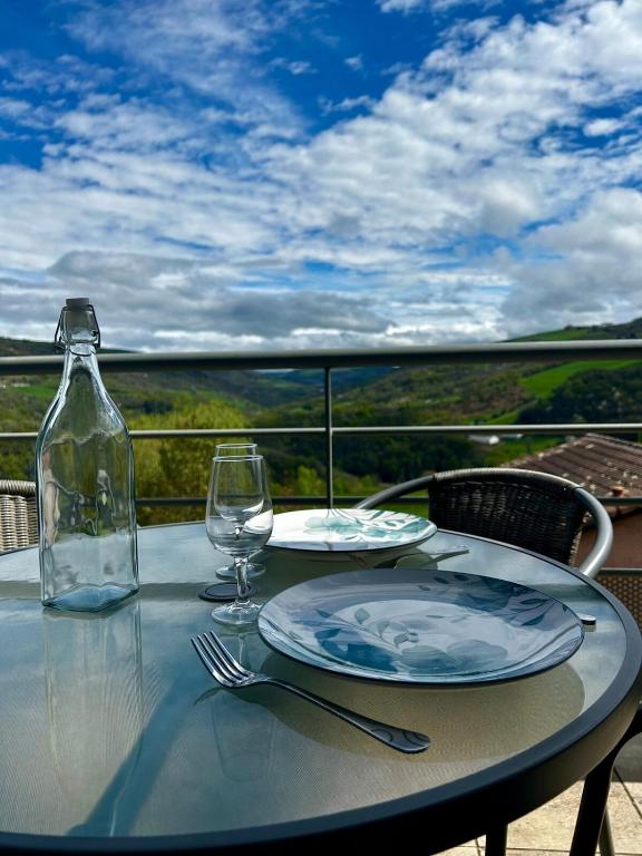 a table with a plate and a bottle and glass at Le Vallon Appartement T2 in Trébas