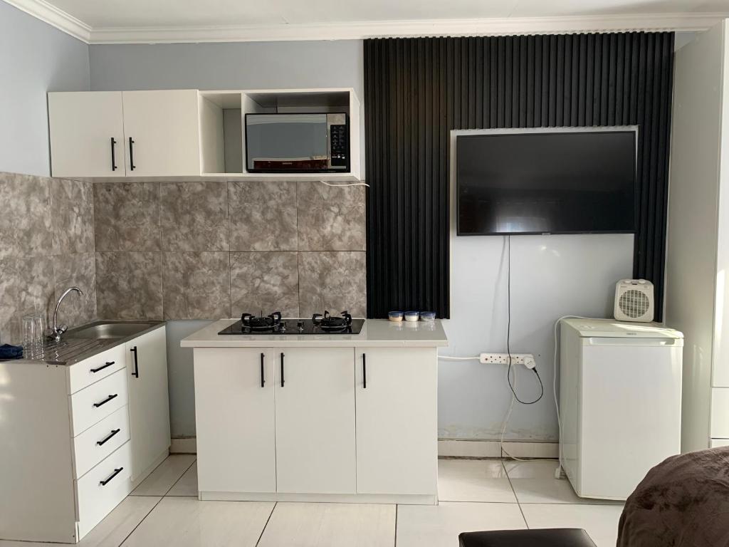 a kitchen with white cabinets and a sink and a microwave at Khainos Self Catering in Khomas Region