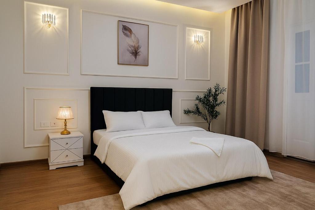 a white bedroom with a large bed and a lamp at Urban Garden Retreat Cozy Studio and Private Patio in Cairo