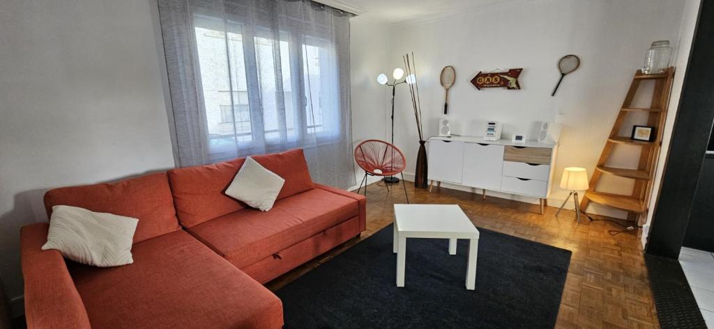 Una sala de estar con un sofá rojo y una mesa. en Maison agréable, quartier calme, en Lorient