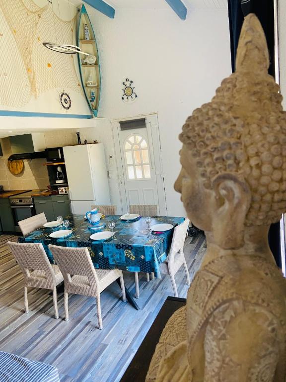 - une cuisine et une salle à manger avec une table et une statue dans l'établissement Maison à 350 m de la plage animaux bienvenus, à Sainte-Marie-la-Mer
