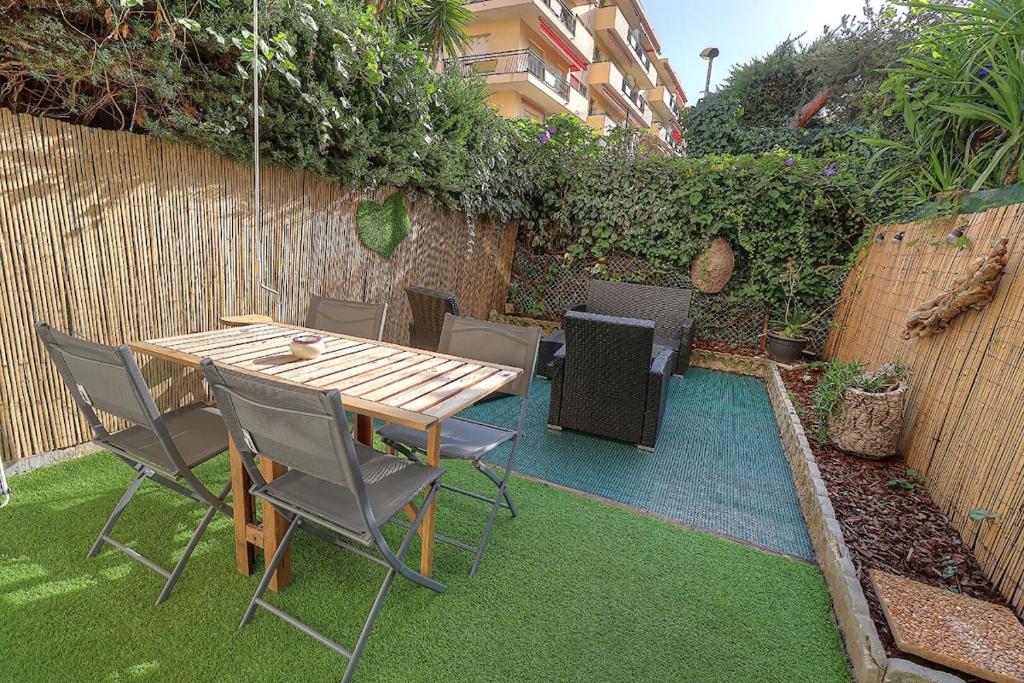 - une table et des chaises en bois dans le jardin dans l'établissement Charmant studio avec jardin, à Antibes