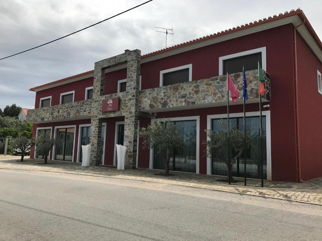 a red building with flags in front of it at Hotel Rural da Catraia in Chão Redondo