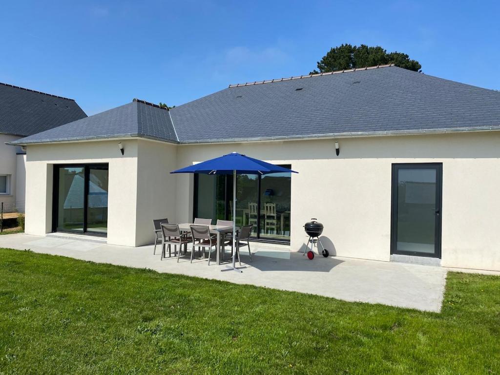 une terrasse avec une table et un parasol bleu dans l'établissement Maison récente bord de mer Binic, à Binic