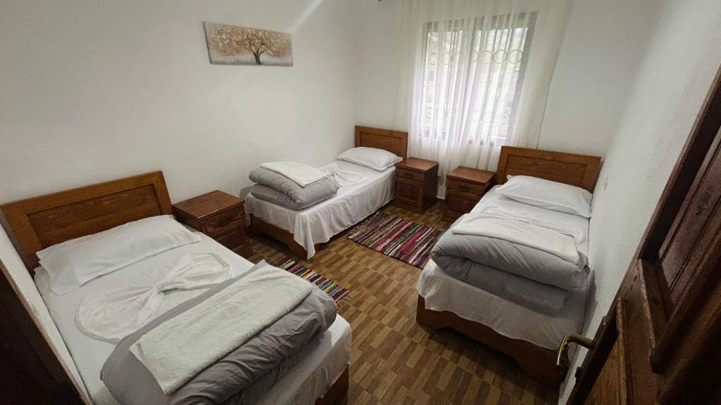 a room with three beds and a window at Guesthouse Lola in Valbonë