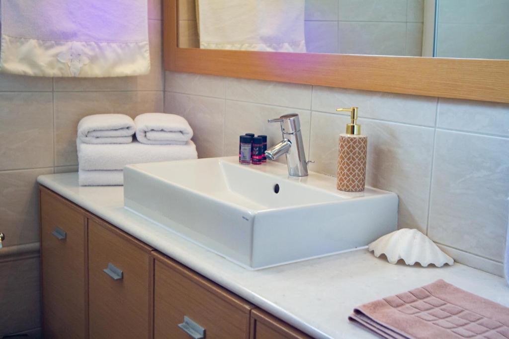 a bathroom with a white sink and a mirror at Elena Hotel in Kozani