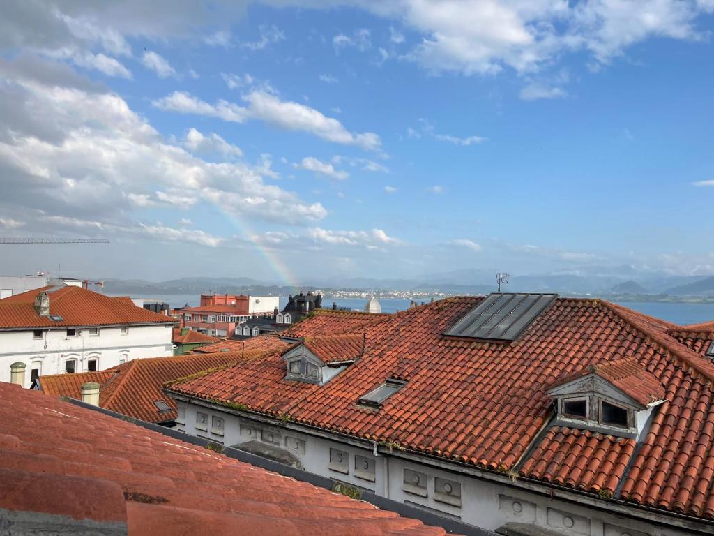 a view of roofs with a rainbow in the background at Apartamento Santa Lucía in Santander