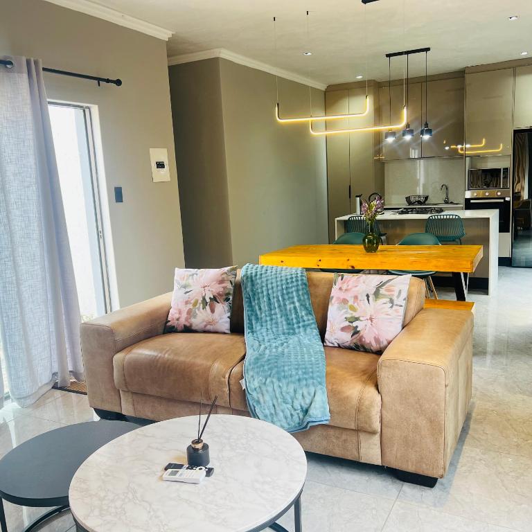 a living room with a couch and a table at Mo's urban nest - with power backup in Sandton