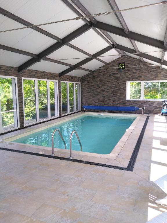 une piscine intérieure avec un plafond et des fenêtres dans l'établissement Le champ bourdon, à Saint-Maur-des-Bois