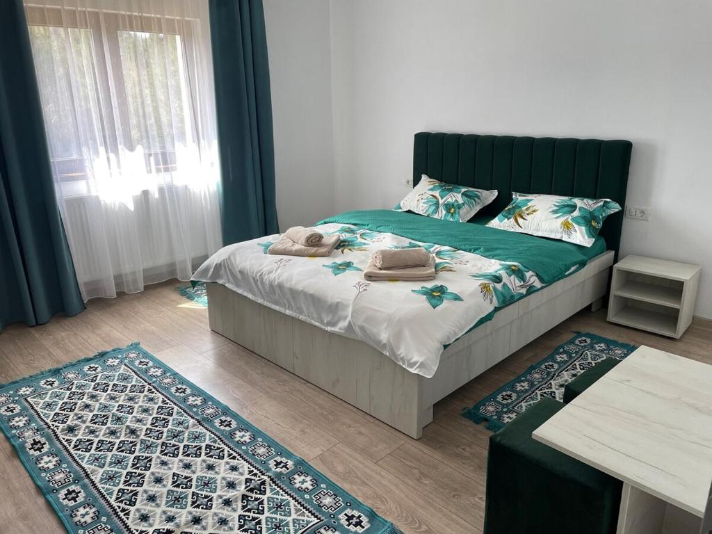 a bedroom with a bed with a green headboard and two rugs at Briza de Munte in Colibiţa