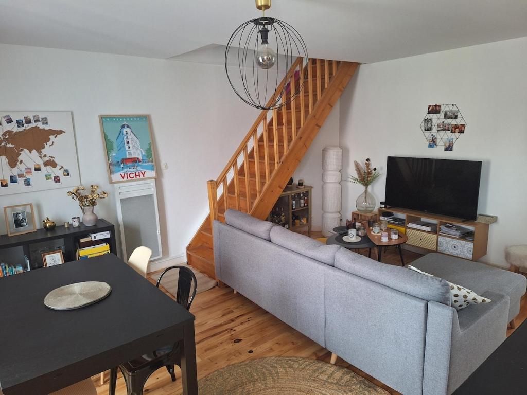 un salon avec un canapé et une télévision dans l'établissement Appartement cosy duplex Vichy, à Vichy
