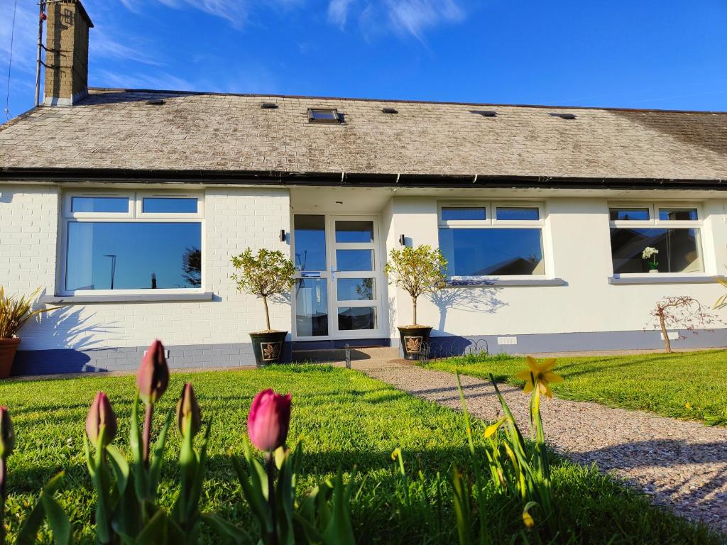 ein weißes Haus mit Blumen davor in der Unterkunft Molly's Cottage in Glenariff