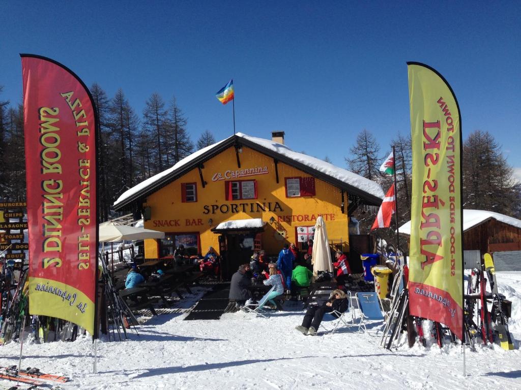 a group of flags in the snow in front of a ski lodge at Chalet Capannina in Sauze dʼOulx