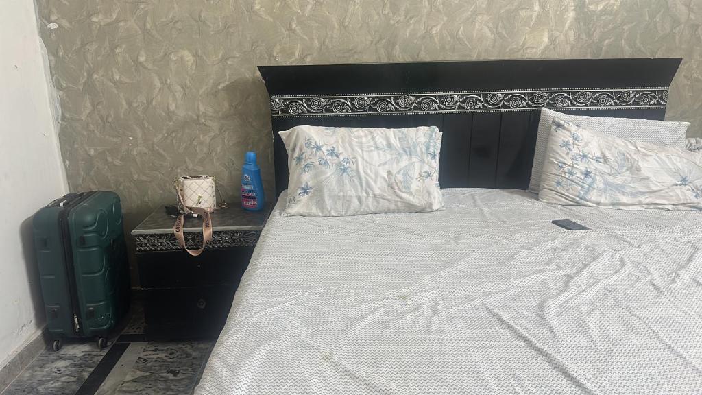 a bed with a black headboard and white sheets and pillows at Ahil house in Lahore
