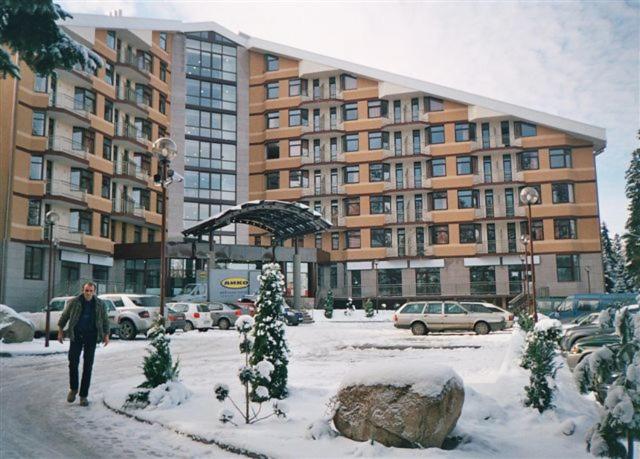 Ein Mann läuft im Schnee vor einem Gebäude in der Unterkunft Flora Apartment 619 in Borowez