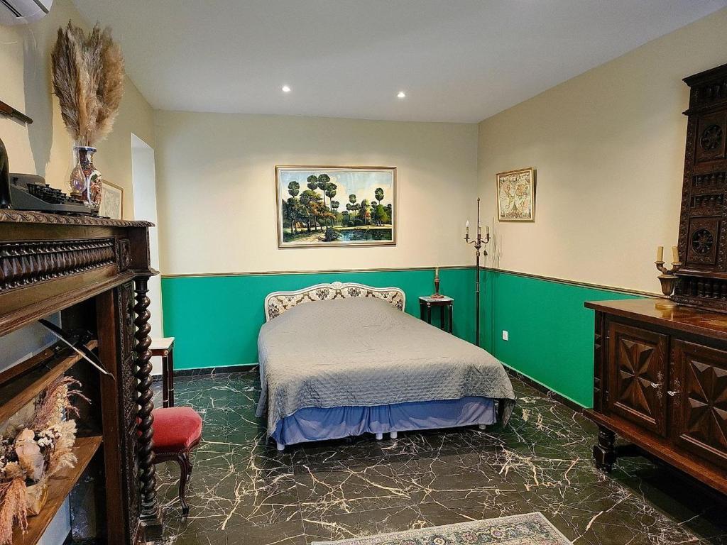 a bedroom with a bed and green walls and a piano at La Perchonniere in Mamers