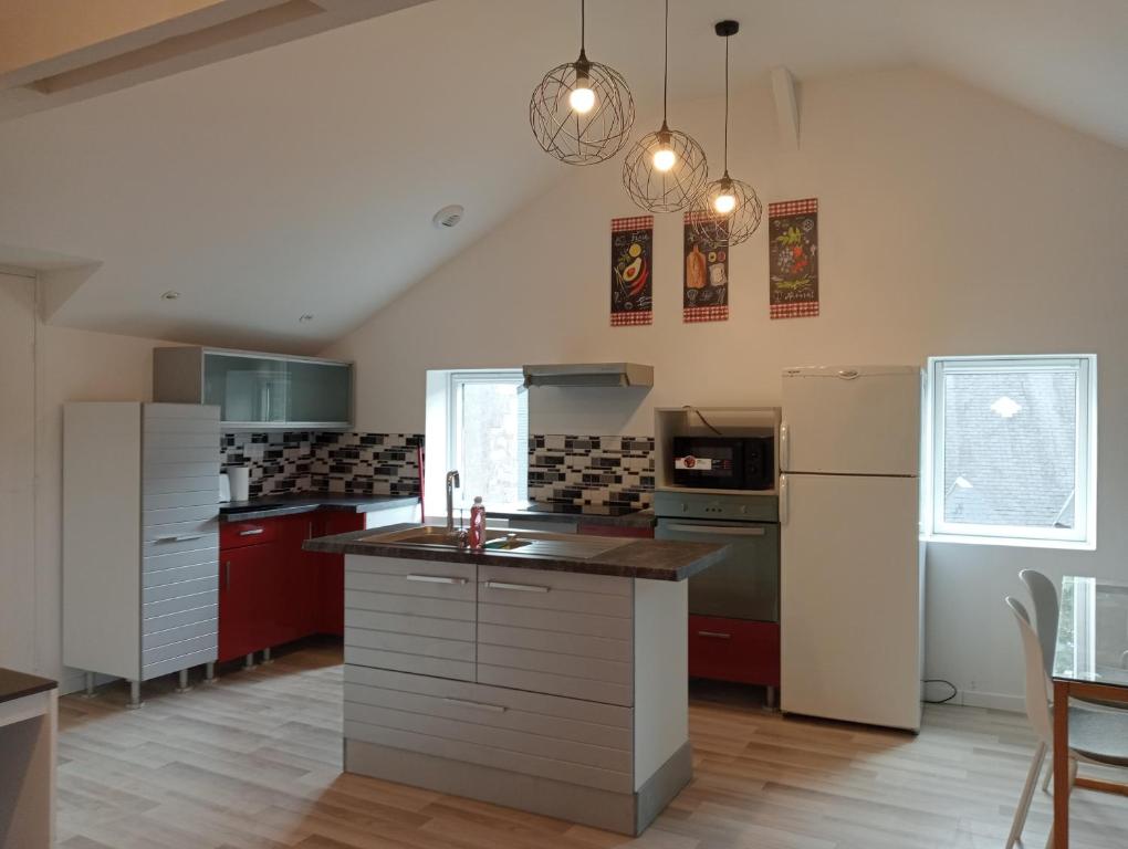 a kitchen with red cabinets and a white refrigerator at Appartement familial en centre ville in Villedieu-les-Poëles