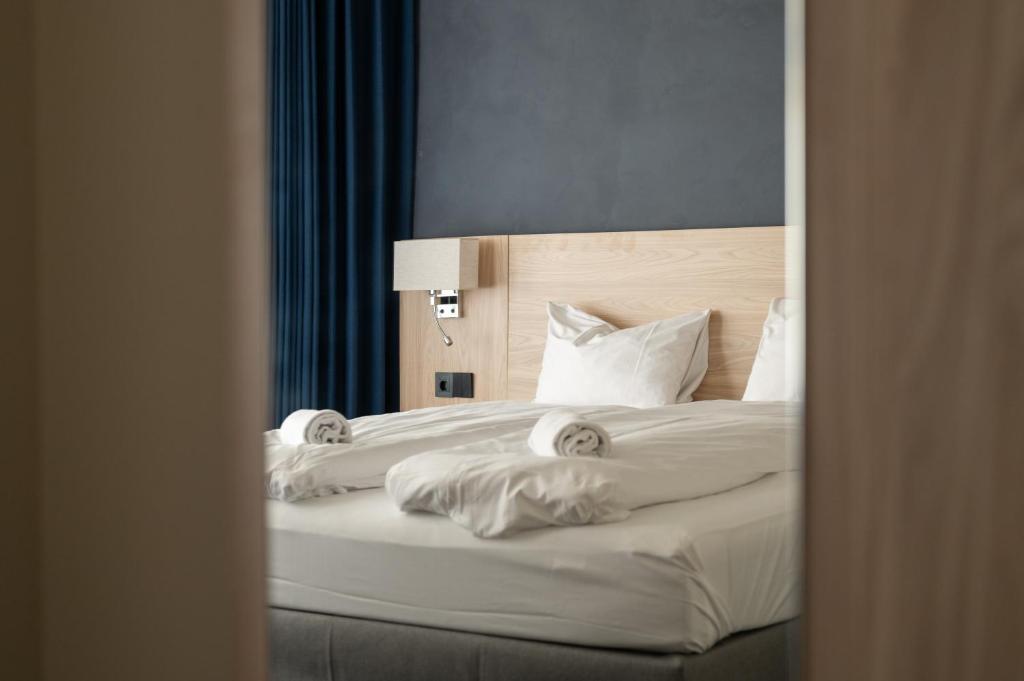 Un dormitorio con una cama con sábanas y almohadas blancas. en BREEZE Hotel Victoria - Self-Service, en Bergen