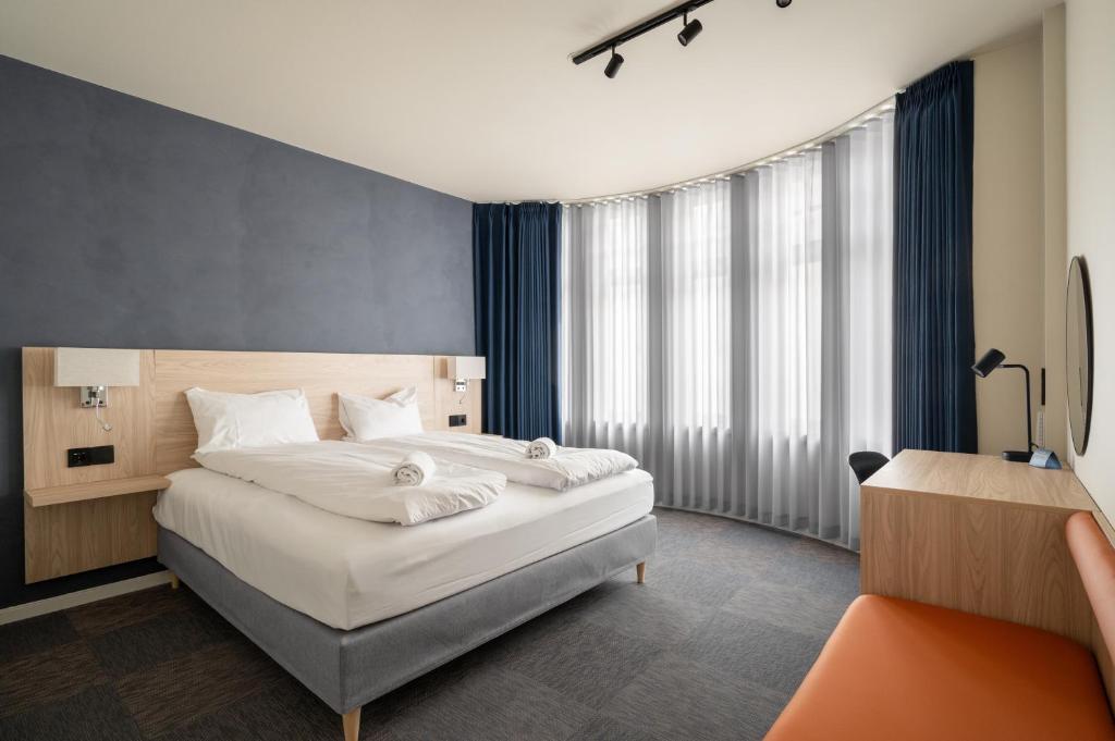 a bedroom with a large white bed and a desk at BREEZE Hotel Victoria - Self-Service in Bergen