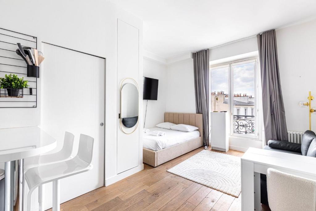 une chambre blanche avec un lit et un miroir dans l'établissement Studio Bastille, à Paris
