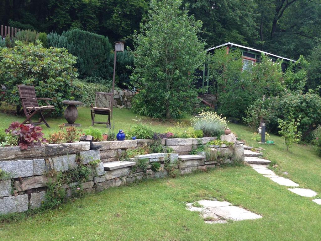 a garden with a stone wall and chairs and flowers at Ferienwohnung Hellerling in Ilsenburg