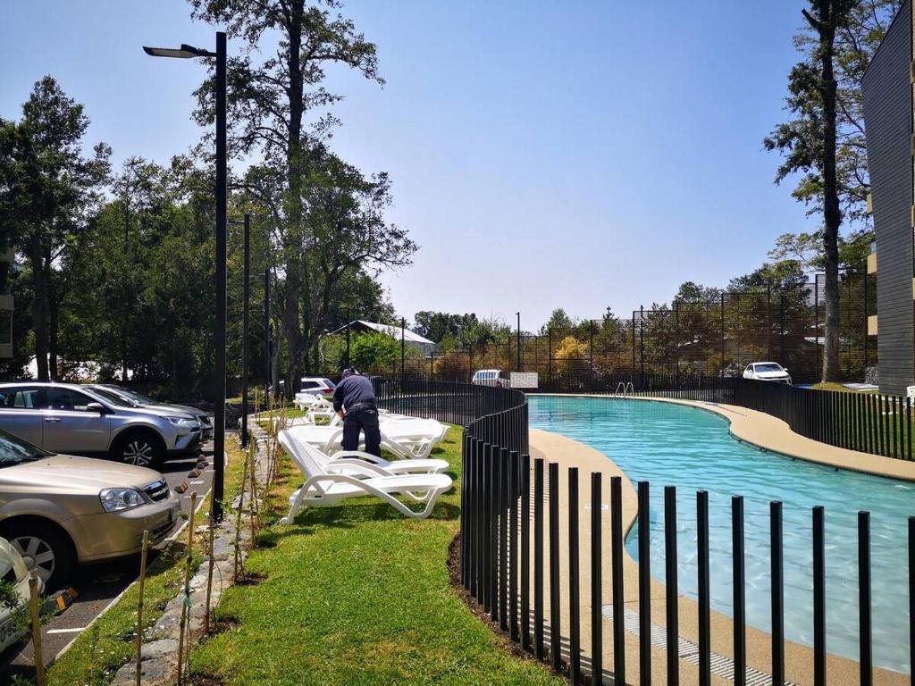 a man standing by a fence next to a swimming pool at Entorno Natural, cerca del centro de Pucón Parking Privado in Pucón