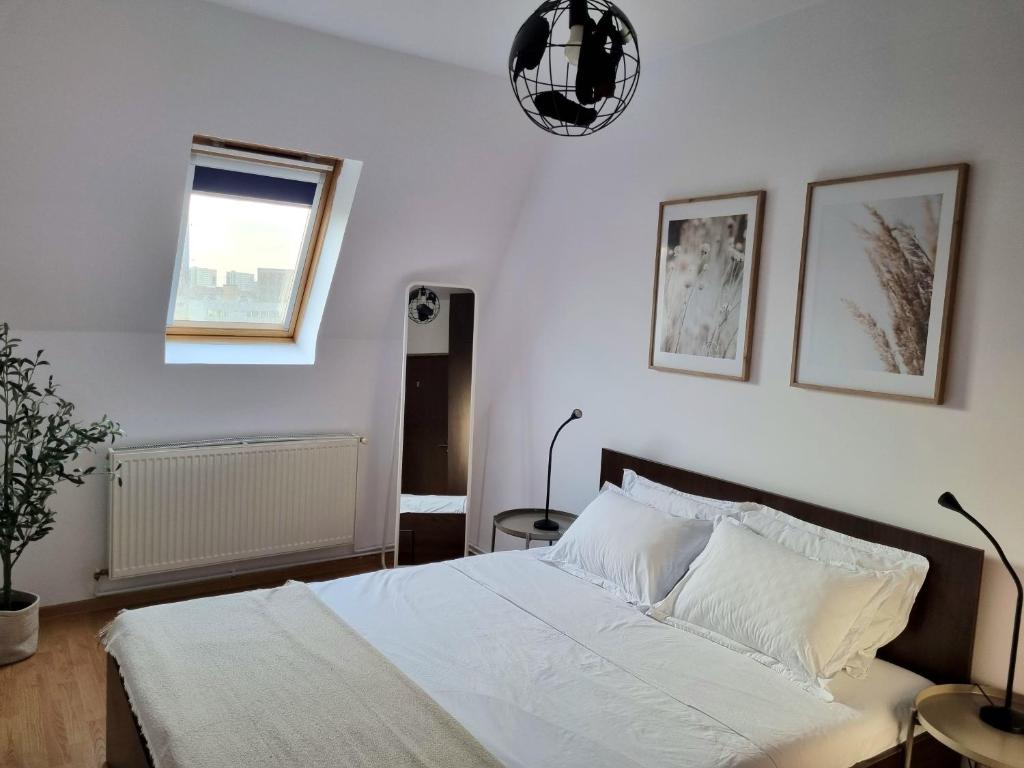 a bedroom with a bed with white sheets and a window at Iulius Town Charm Cozy Apartments in Timişoara