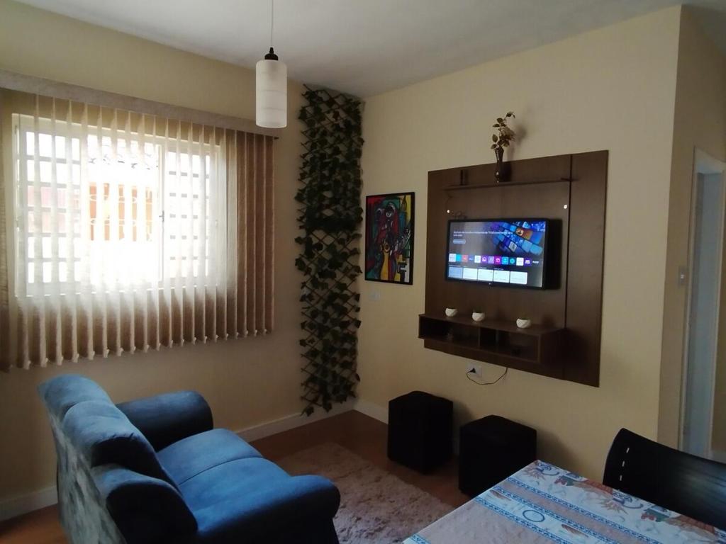 a living room with a blue couch and a tv at Casa com 01 qto 42m2 in Poços de Caldas